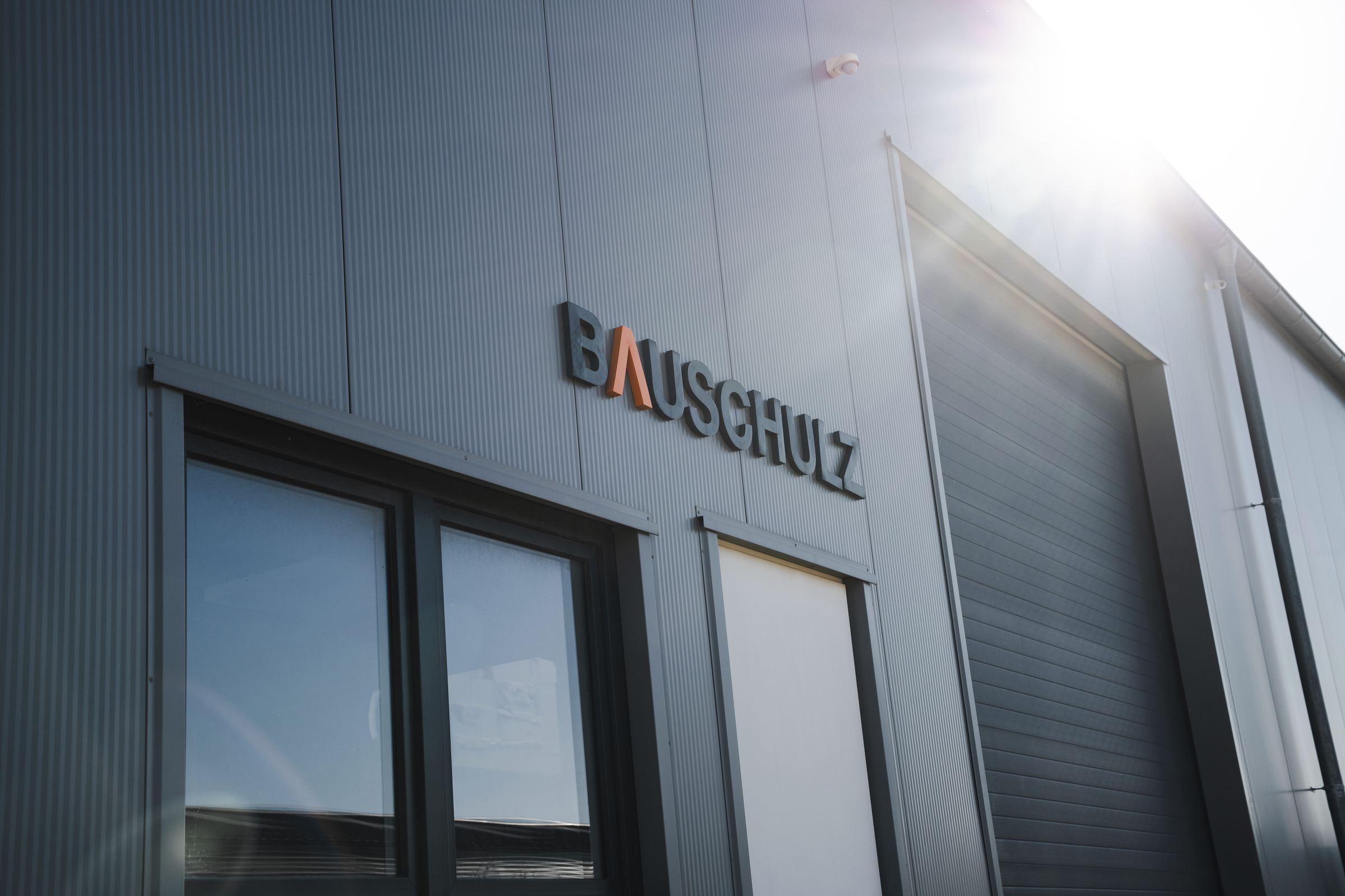 Halle von BAUSCHULZ mit Firmenschriftzug in der Sonne