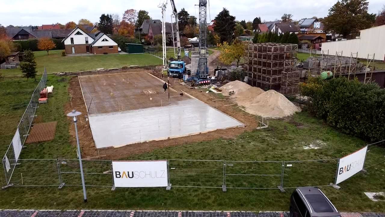 Bodenplatte wird betoniert, am Bauzaun Banner von BAUSCHULZ, aus der Luft