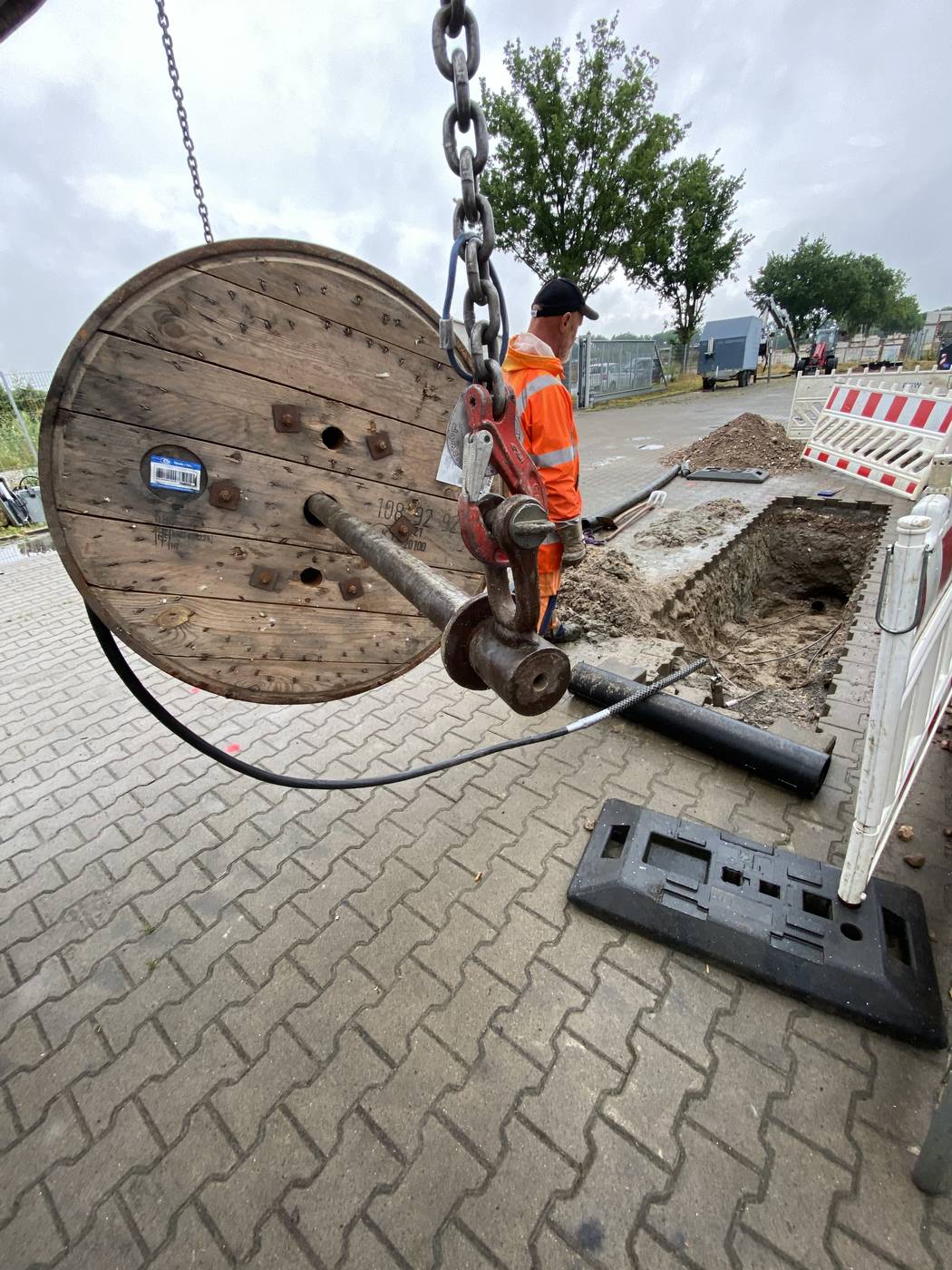 Kabelbau: Kabel wird von der Trommel in ein Schutzrohr in der Baugrube eingezogen