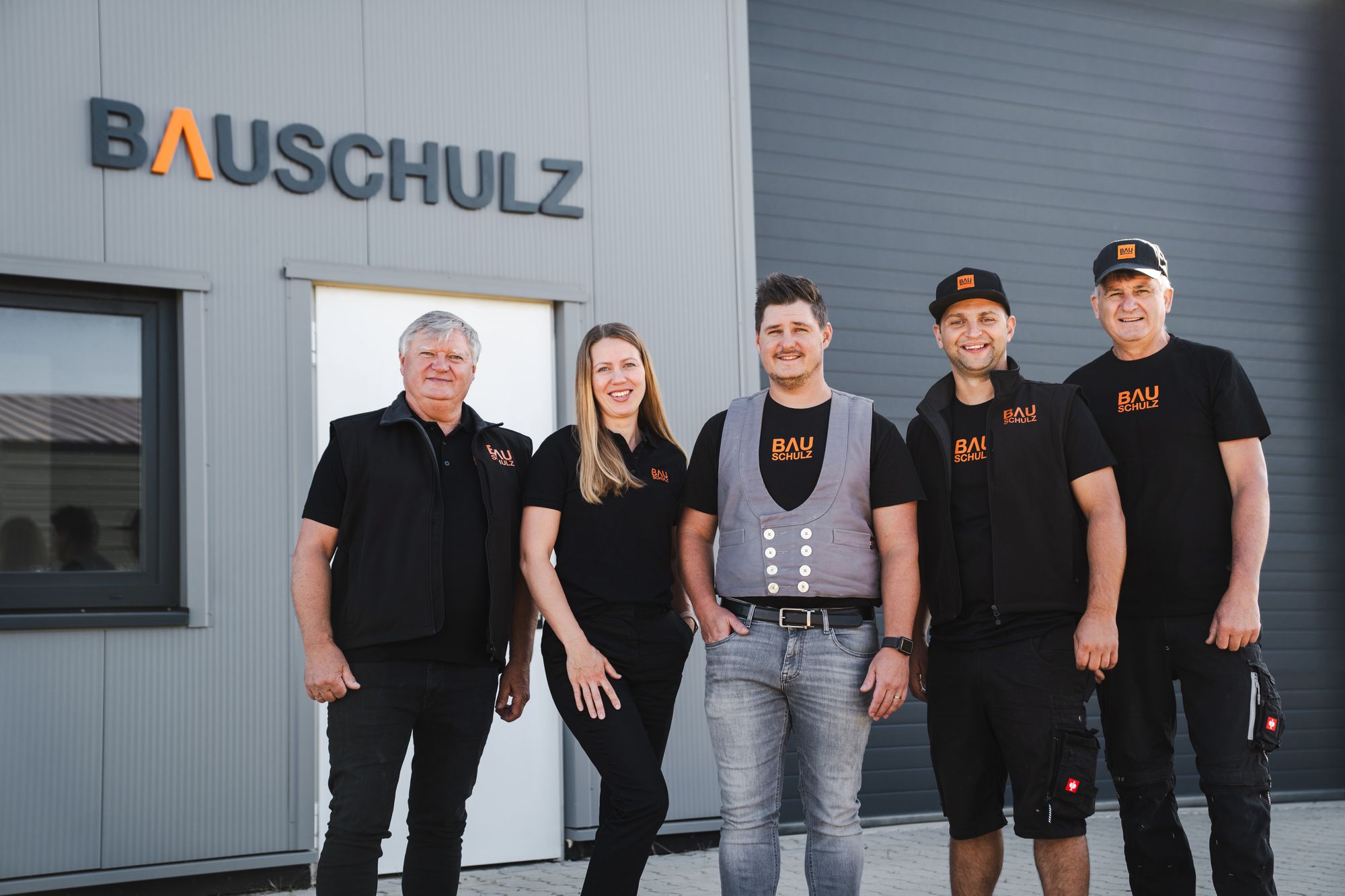 Das Team von BAUSCHULZ vor der Halle mit dem Firmenschriftzug